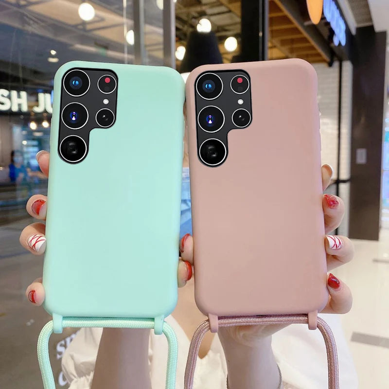 Two smartphone cases, one mint green and one pink, both with attached lanyards and a cutout for a multi-lens camera array.