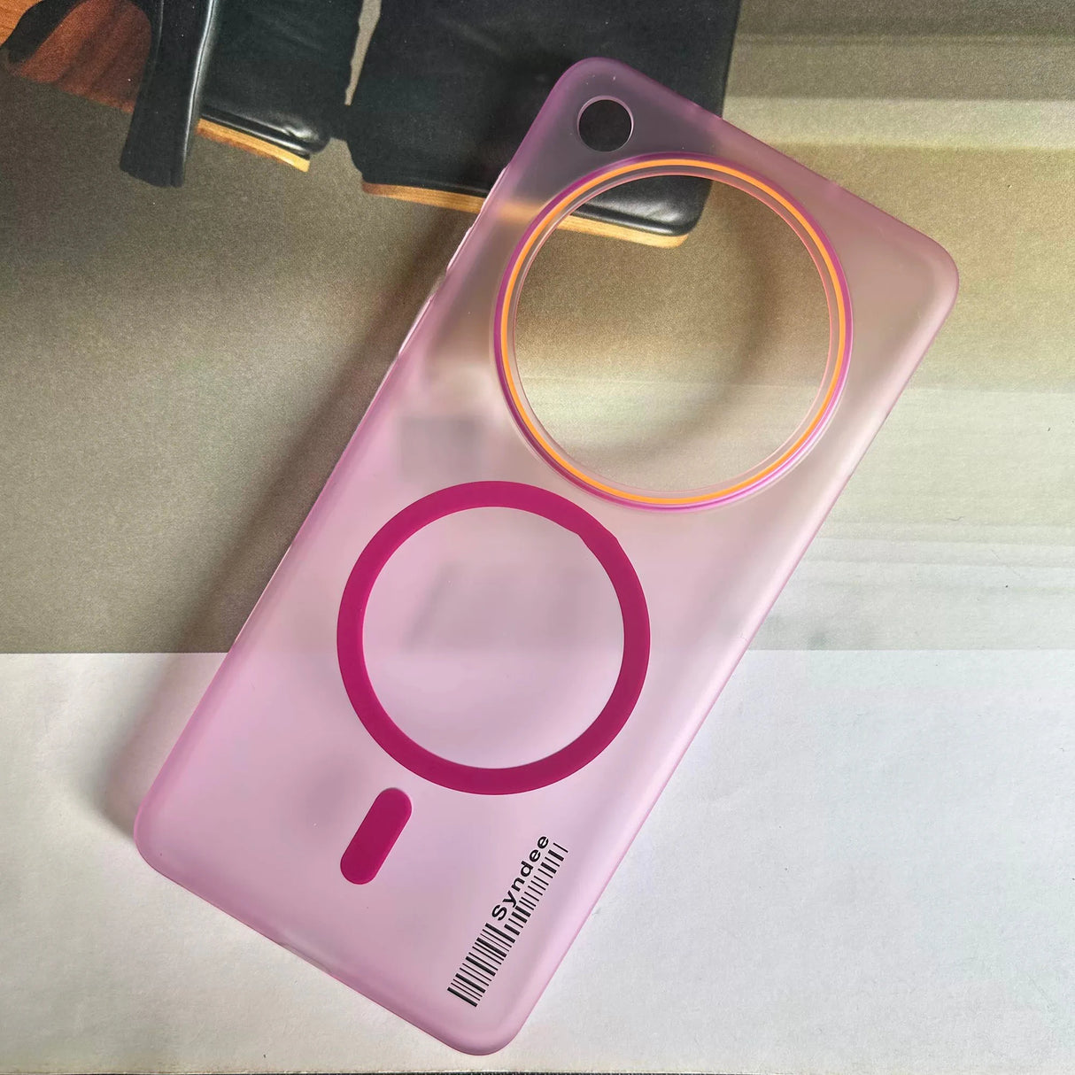 Pink transparent phone case with a circular camera cutout and a magnetic charging ring.