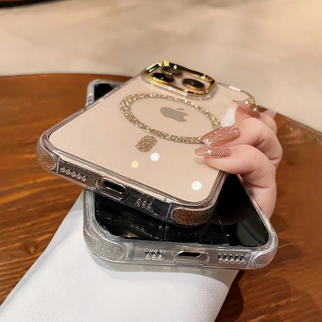 Clear iPhone case with glitter accents, a gold camera ring, and a sparkly magnetic charging ring around the Apple logo.