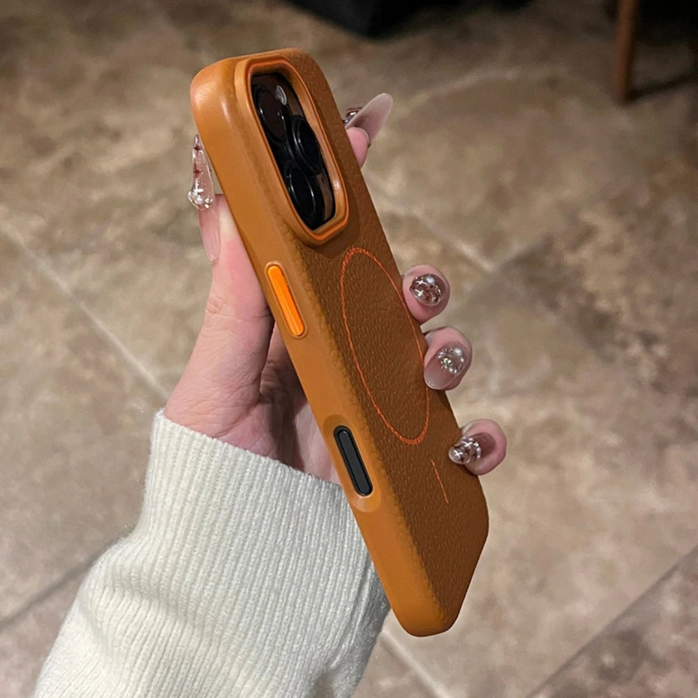 A person holding a brown leather phone case with orange buttons and a circular design.