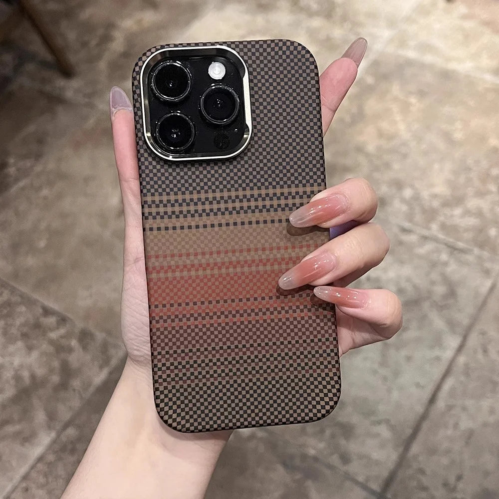A smartphone with a checkered brown and black patterned case, featuring a camera module with three lenses and a flash, held by a hand with long, clear-to-pink gradient nails.