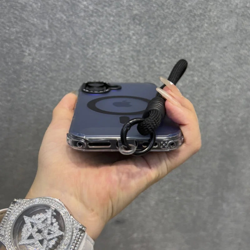 A clear iPhone case with a black MagSafe ring and a black braided wrist strap.