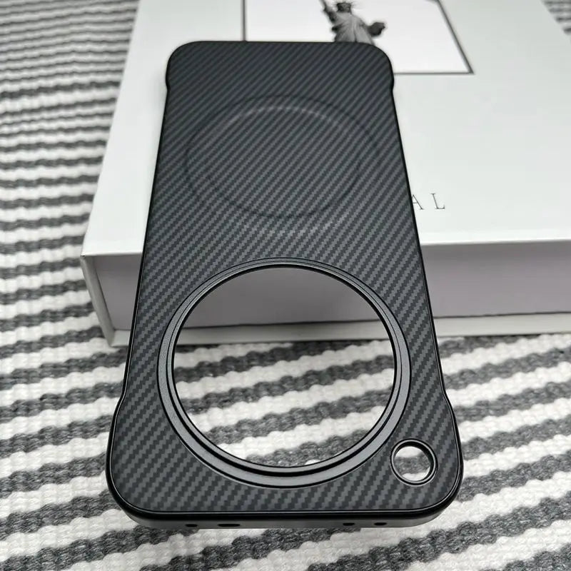 Black carbon fiber phone case with a large circular cutout and a smaller circular cutout.
