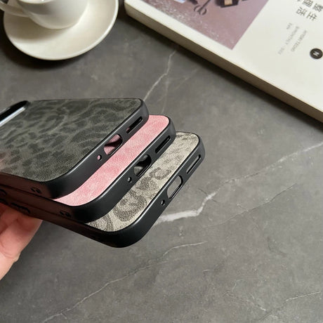 Stacked leopard print phone cases in black, pink, and gray.