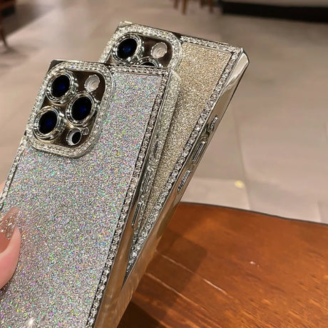 Two sparkly silver iPhone cases with diamond-encrusted camera cutouts and side bezels.
