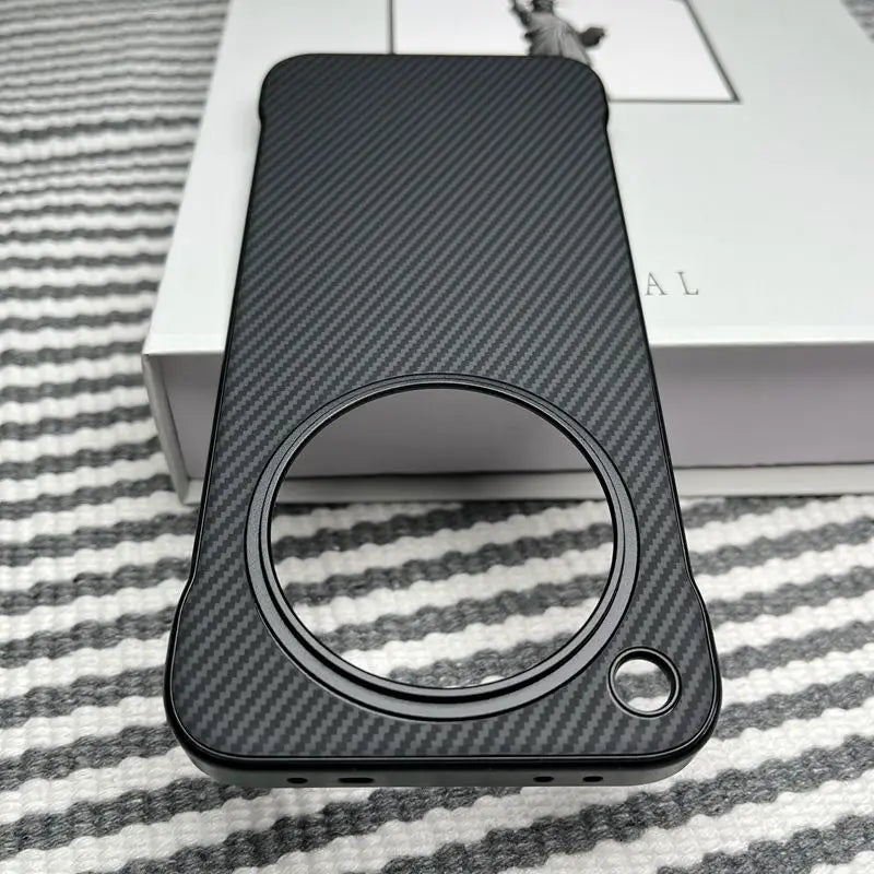 Black carbon fiber phone case with a large circular camera cutout and a smaller circular cutout for a button or sensor.