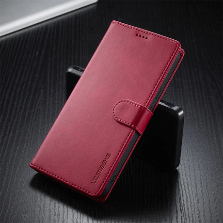 A closed, red leatherette phone case with a magnetic strap.