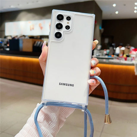 A clear phone case with a camera cutout, lanyard loops, and an attached light blue cord with gold accents.