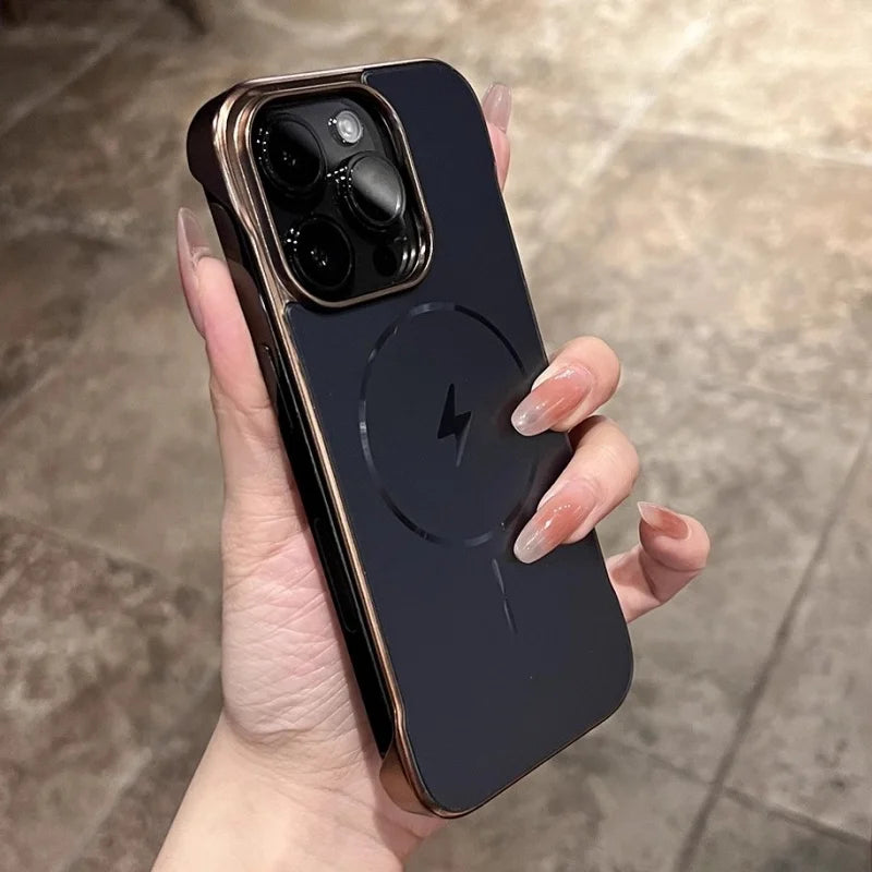 A person holding a dark smartphone in a case with gold edges and a circular magnetic charging symbol.
