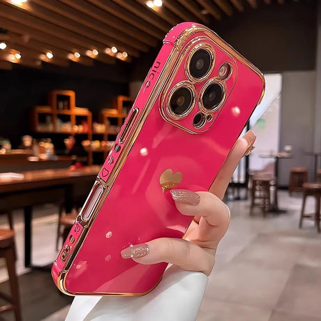 Shiny hot pink iPhone case with gold accents and a heart-shaped stand.