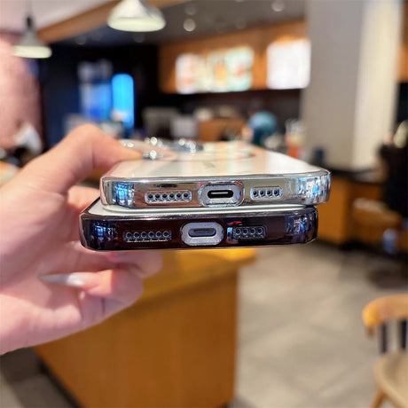 Two smartphone cases, one clear with a silver edge and one dark with a black edge, both featuring cutouts for charging ports and speakers.