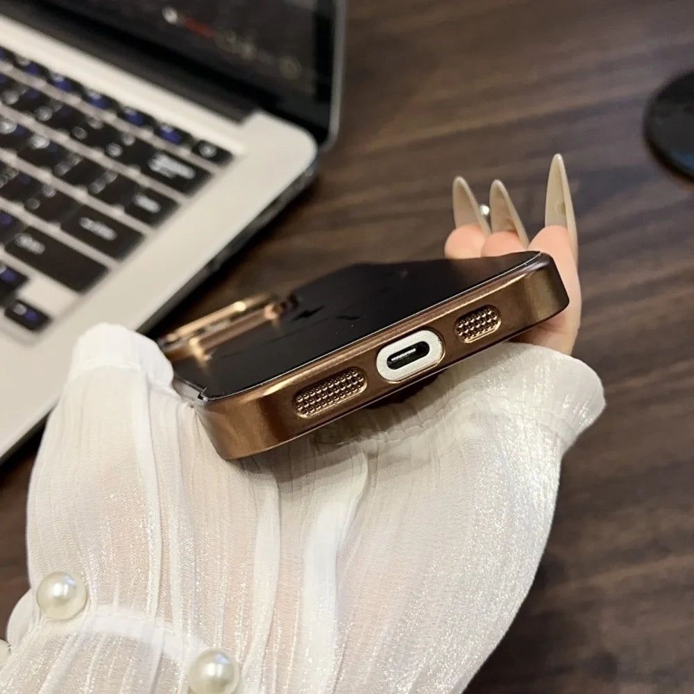 A smartphone with a glossy black back and a shiny bronze-colored protective case, featuring a USB-C charging port and speaker grilles.