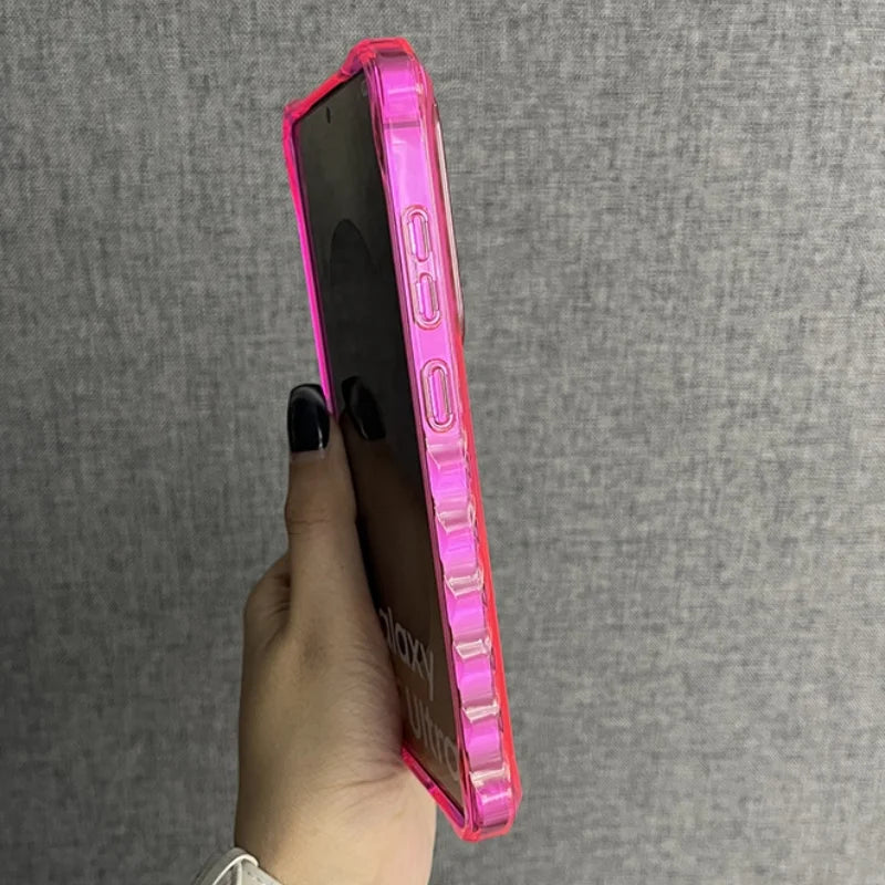 A hand holding a bright pink, clear smartphone case.