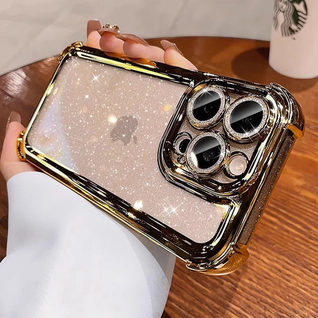 A clear iPhone case with a sparkling glitter back, gold metallic frame, and a matching gold camera lens protector embellished with rhinestones.