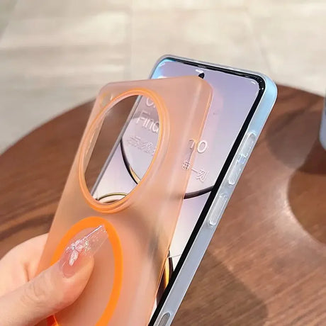 A transparent, peach-colored phone case with a circular camera cutout and an orange ring design, being held next to a smartphone.