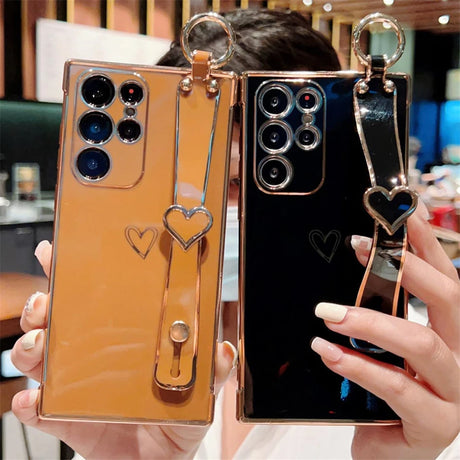 Two smartphones with heart-shaped strap holders in gold and black.