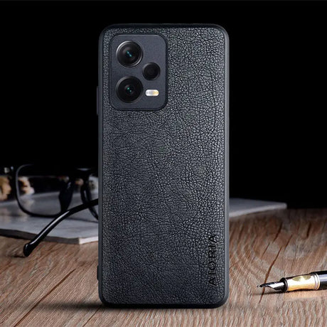 the back of a black leather case with a pen and glasses on it
