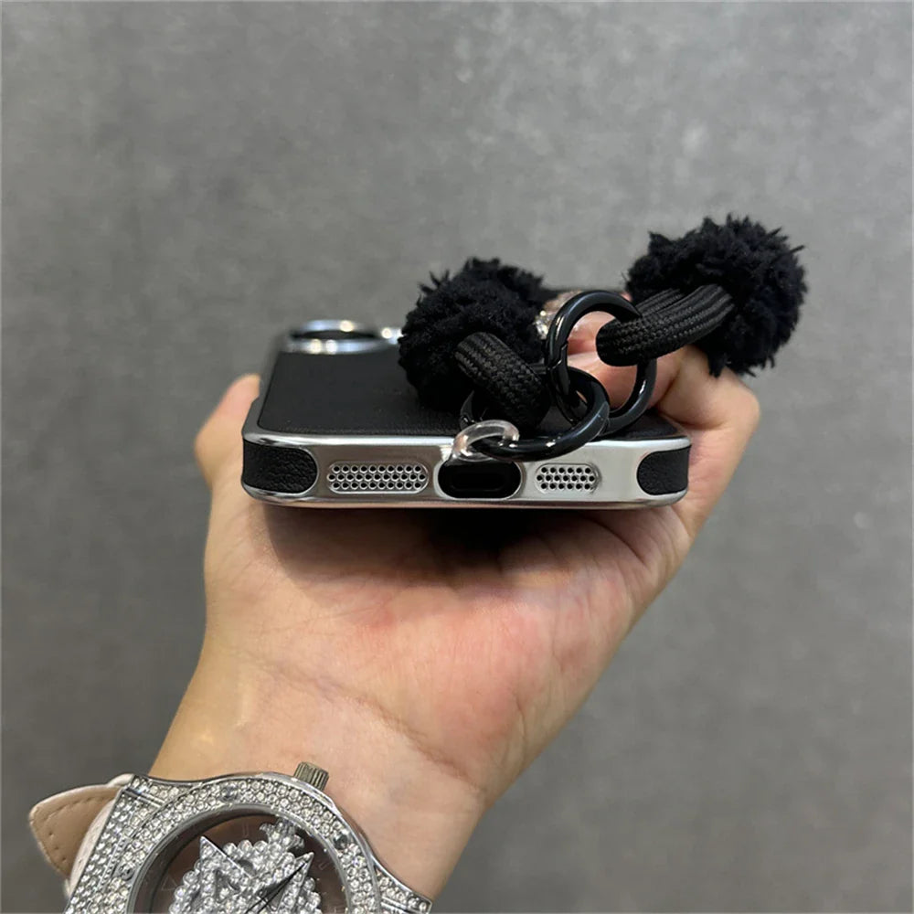 Black phone case with pom-pom charm.