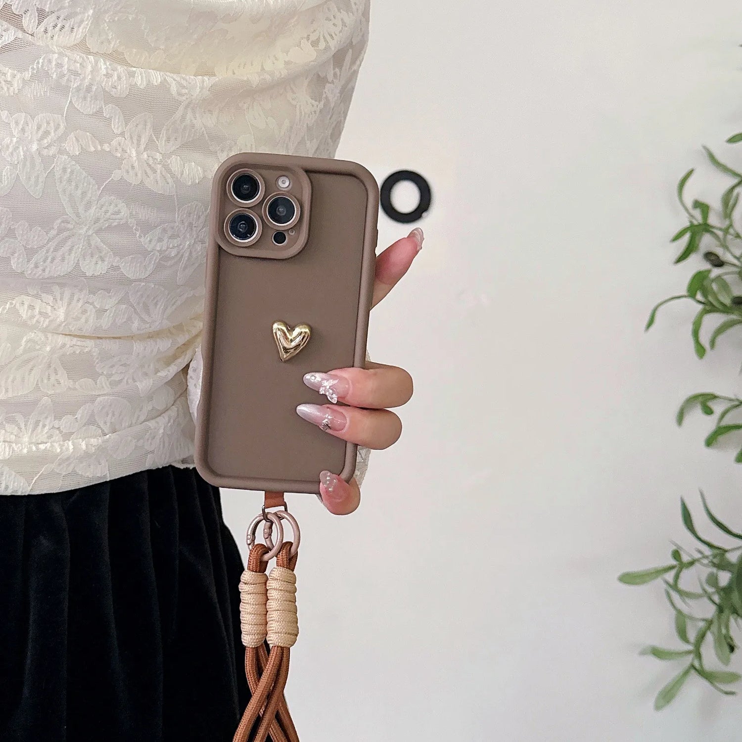 Brown phone case with heart charm and lanyard.