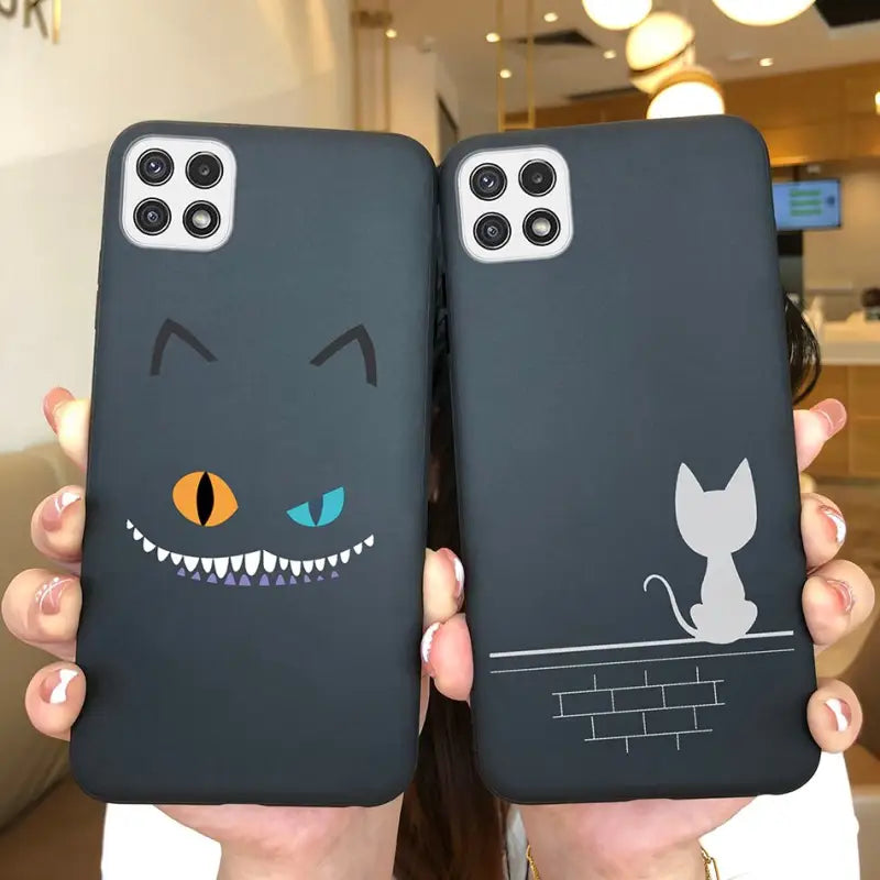 a person holding up two black phone cases