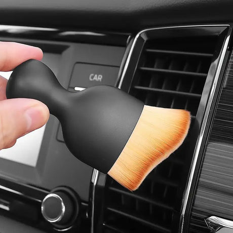 a hand holding a brush in the dashboard of a car