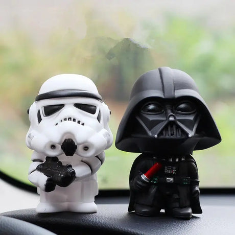 a pair of star wars action figures sit on the dashboard of a car