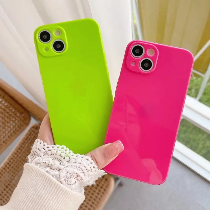 a woman holding a pink and green phone case