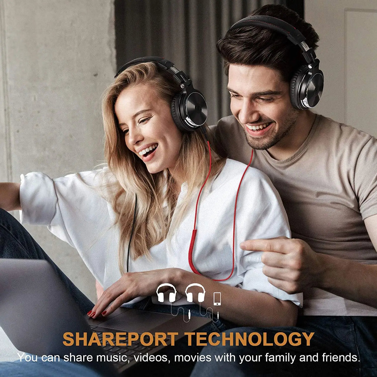 A couple wearing headphones and smiling while looking at a laptop together.