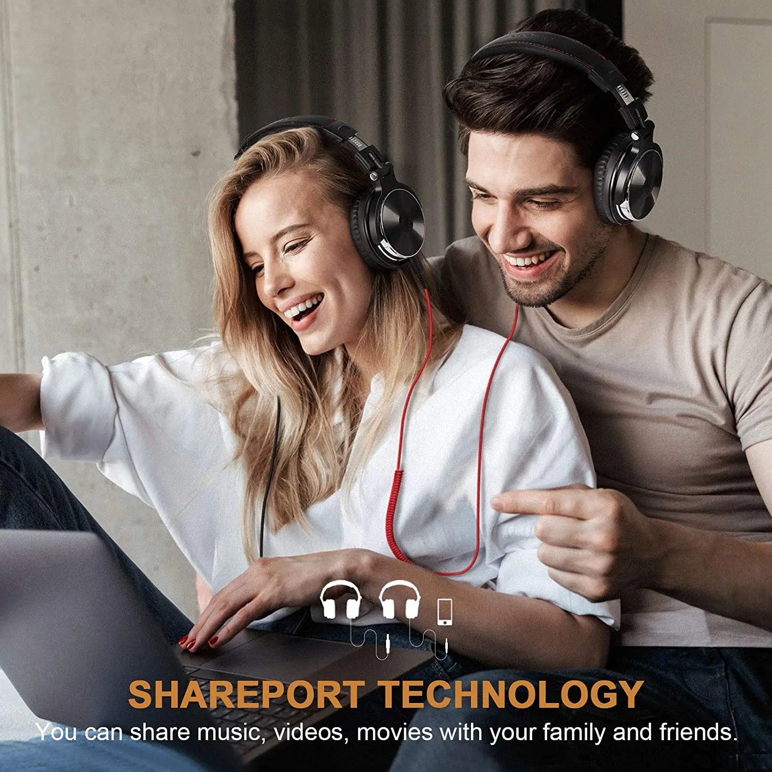 A couple wearing headphones and smiling while looking at a laptop together.