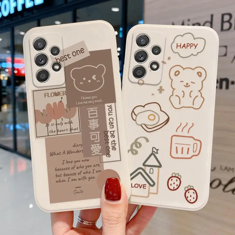 a woman holding up two iphone cases with a drawing of a bear