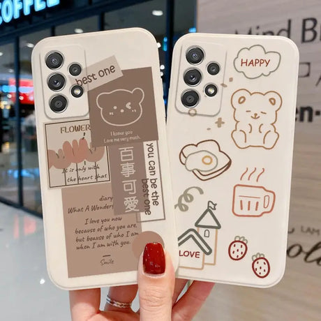 a woman holding up two iphone cases with a drawing of a bear