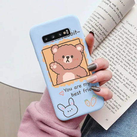 a woman holding a phone case with a bear on it
