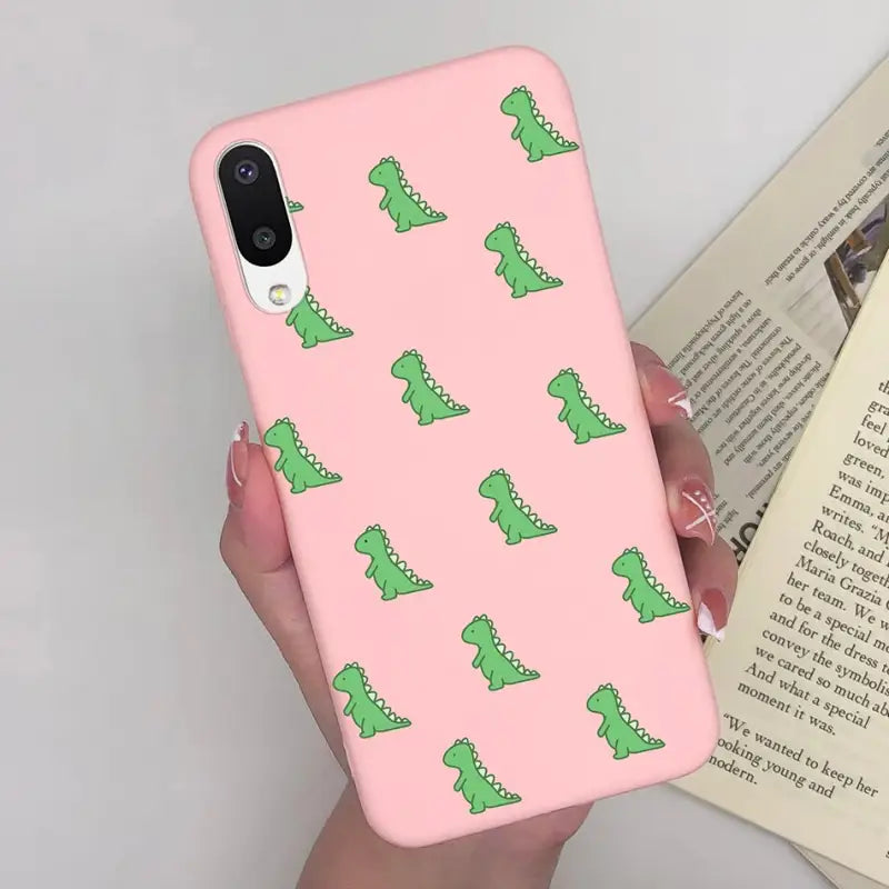 a woman holding a pink phone case with green alligators on it