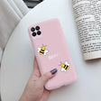 a woman holding a pink phone case with a bee on it