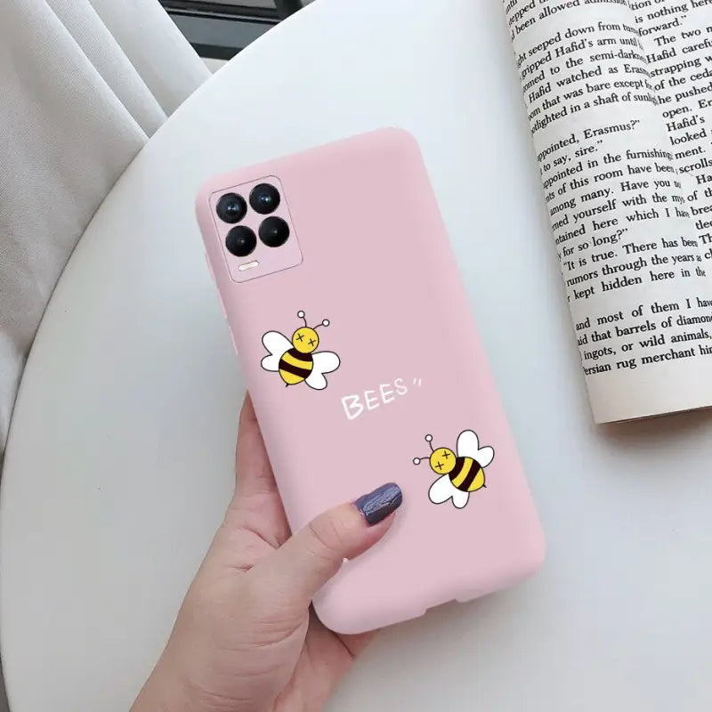 a woman holding a pink phone case with a bee on it
