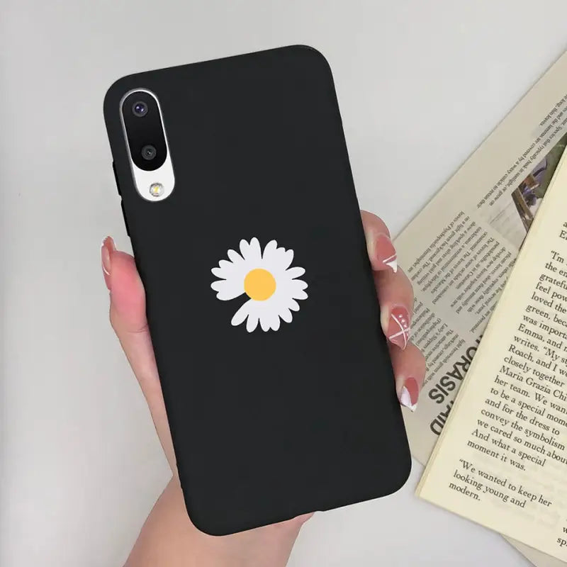 a woman holding a phone case with a daisy on it