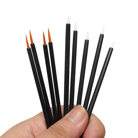 a hand holding a set of black and orange paint brushes