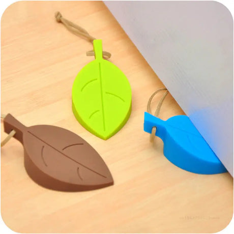 a green leaf and a blue leaf on a wooden floor