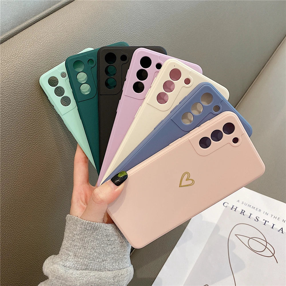 A fan of colorful silicone phone cases, with one pastel pink case featuring a small gold heart design.