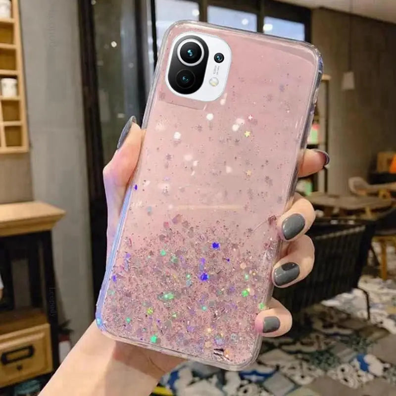 a woman holding a pink glitter phone case
