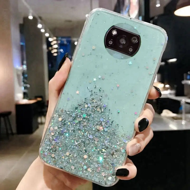 a woman holding up a phone case with glitter