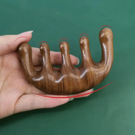 a hand holding a wooden object with a red thread