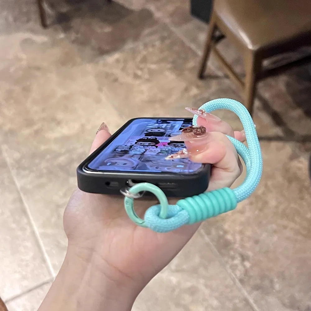 Hand holding phone with blue wrist strap.