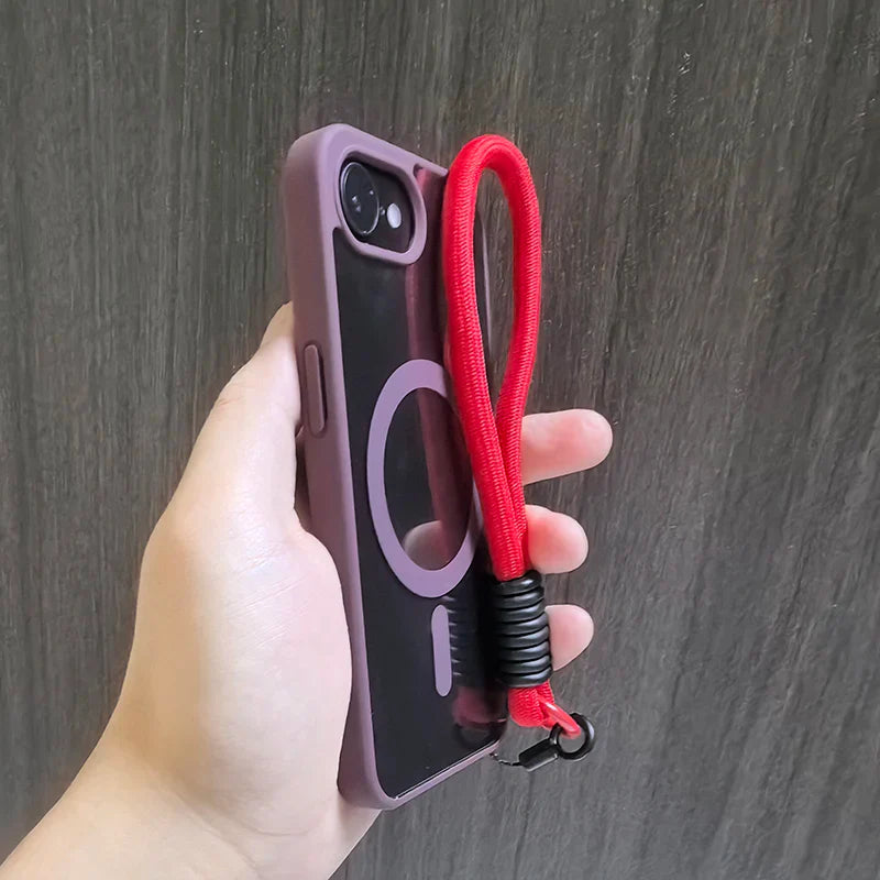 Hand holding a phone in a purple case with a red wrist strap.