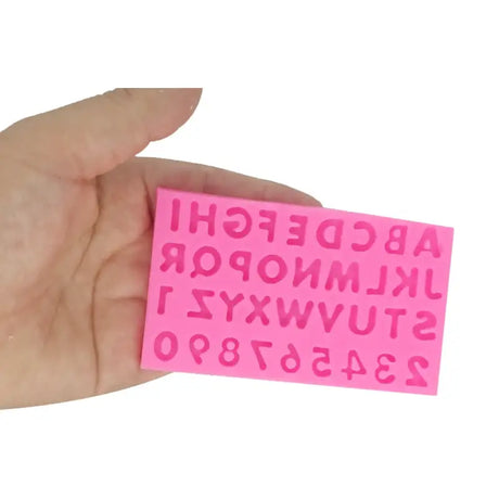 a hand holding a pink sticky stick with the letters