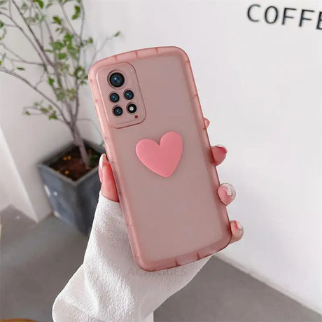 a woman holding a pink heart phone case