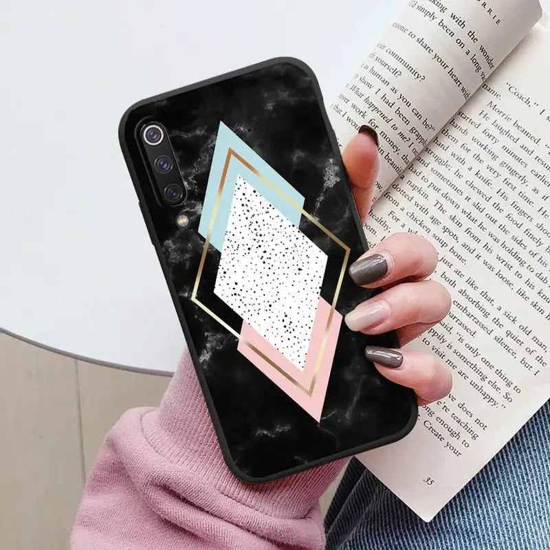 a woman holding a phone case with a geometric design