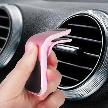 a hand holding a pink car air vent