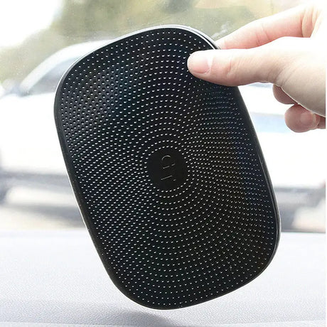 someone holding a black speaker in their hand in a car