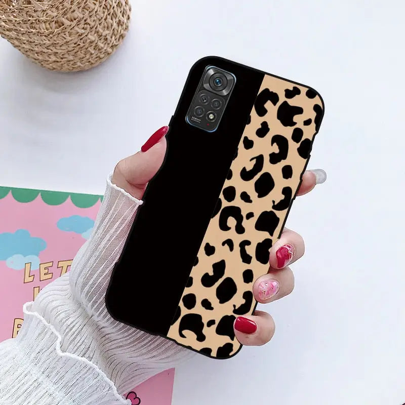 a woman holding a phone case with a leopard print